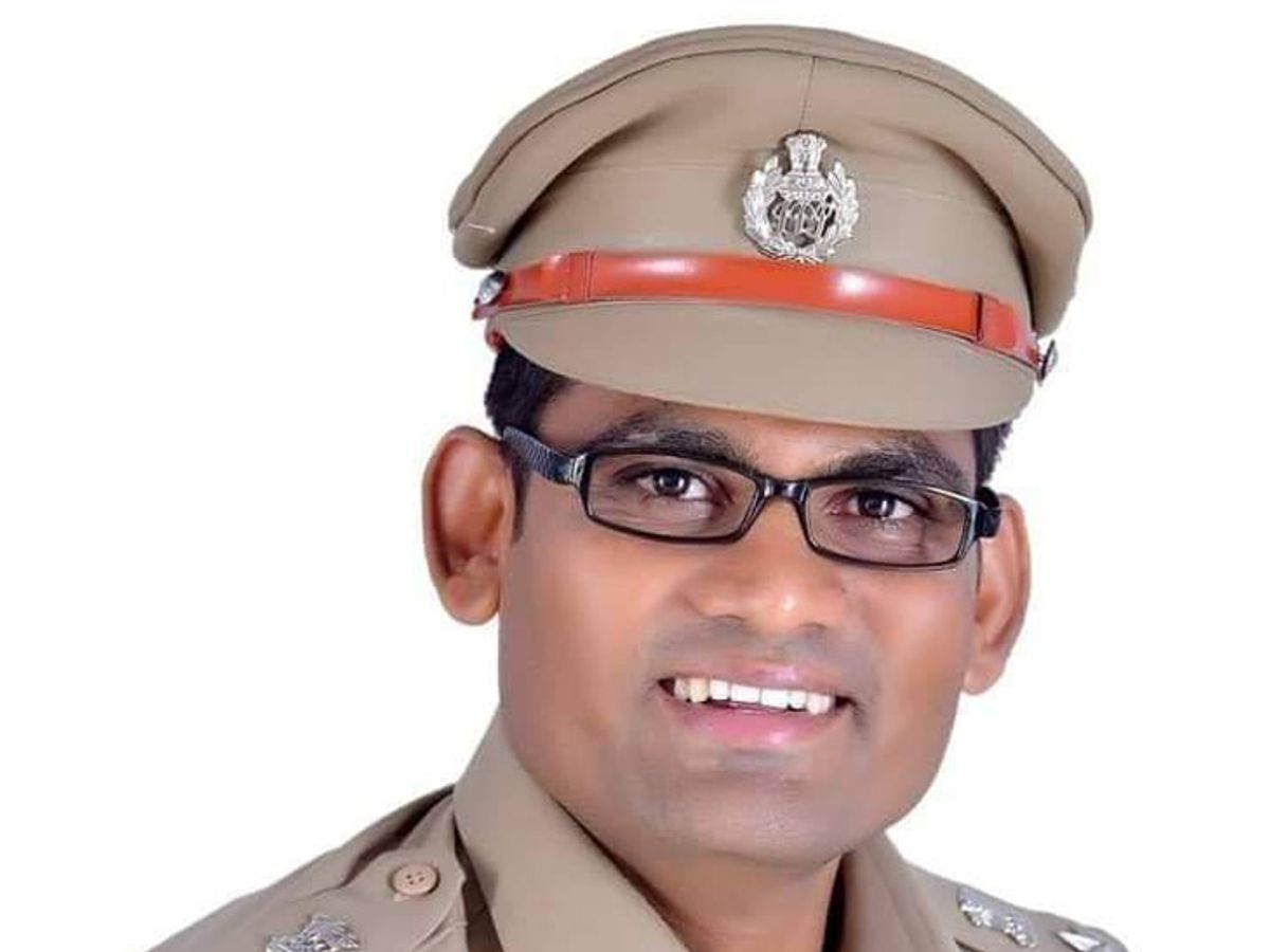 Close portrait of Sanjay Kharat smiling, wearing a peaked service cap with the state police badge, against a plain white background.