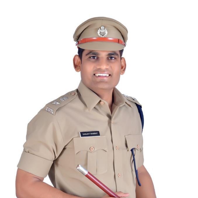 Sanjay Kharat standing in ceremonial police dress with peaked cap, lanyard and baton, against a plain white background.