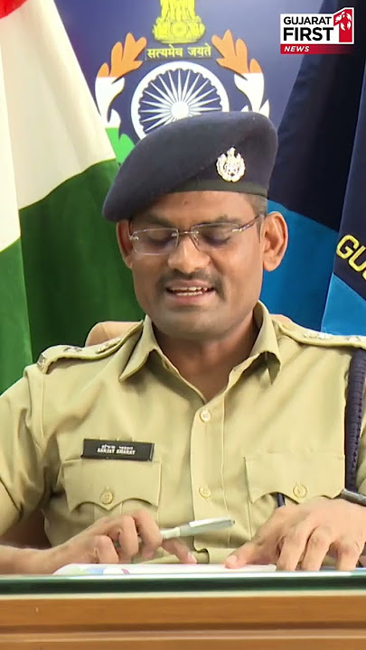 Sanjay Kharat seated at his office desk reviewing a document, with the national flag and departmental standards behind him.